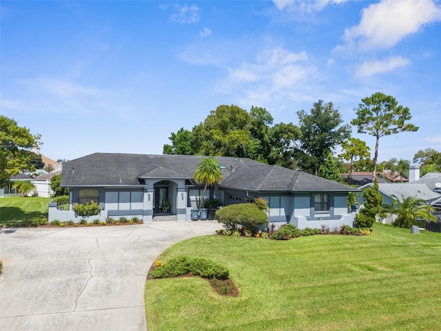 view of front facade with concrete driveway, roof with shingles, a front yard, and stucco siding