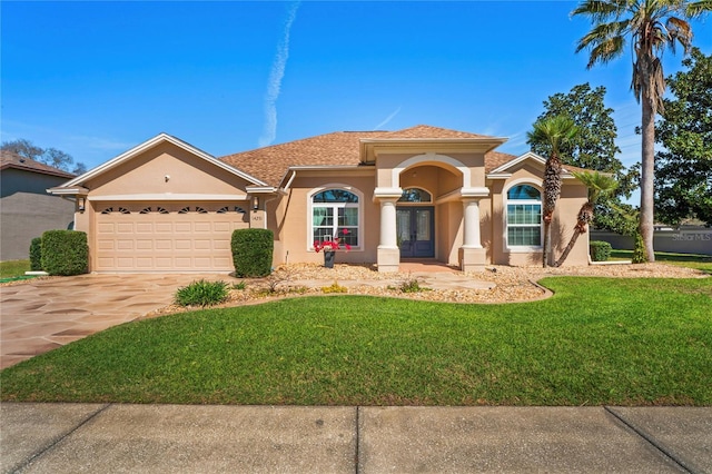 mediterranean / spanish house featuring french doors, stucco siding, a front yard, a garage, and driveway