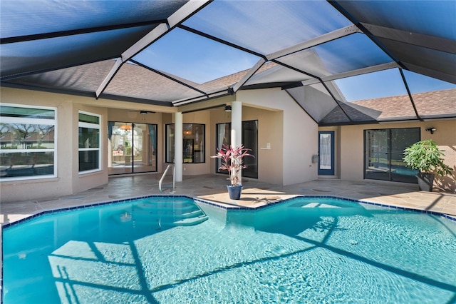 outdoor pool with glass enclosure, a ceiling fan, and a patio