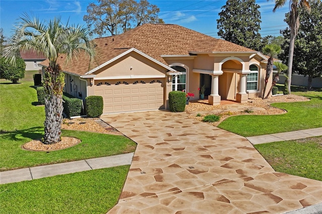 mediterranean / spanish home with a front yard, driveway, an attached garage, and stucco siding