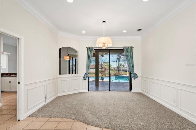 empty room featuring light tile patterned floors, recessed lighting, light colored carpet, ornamental molding, and wainscoting