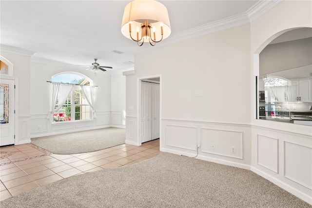 spare room with crown molding, light tile patterned floors, light colored carpet, visible vents, and ceiling fan with notable chandelier