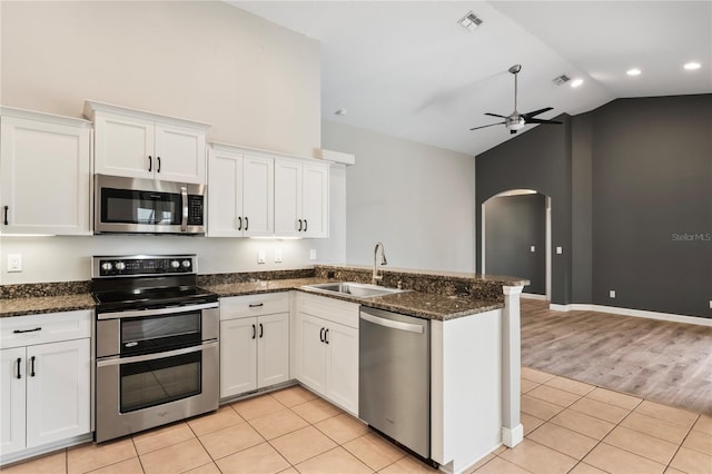 kitchen with arched walkways, a ceiling fan, appliances with stainless steel finishes, a sink, and light tile patterned flooring