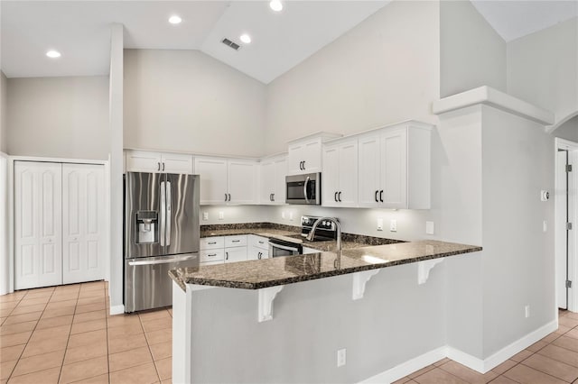 kitchen with light tile patterned floors, visible vents, a breakfast bar, a peninsula, and stainless steel appliances