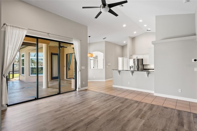 unfurnished living room with high vaulted ceiling, recessed lighting, wood finished floors, a ceiling fan, and baseboards