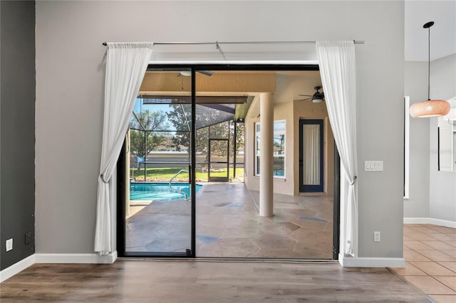 entryway with a ceiling fan, a sunroom, baseboards, and wood finished floors