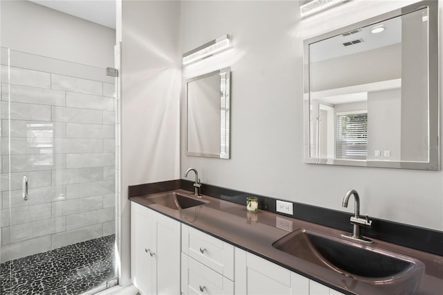 full bath featuring visible vents, a sink, a shower stall, and double vanity