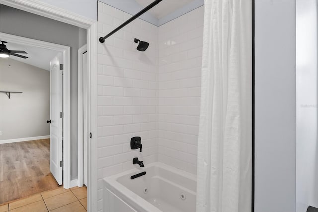 full bath featuring a combined bath / shower with jetted tub, baseboards, a ceiling fan, and tile patterned floors