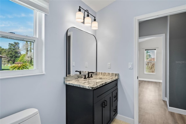 half bathroom with toilet, baseboards, and vanity