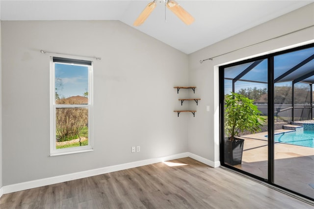 unfurnished room featuring a sunroom, vaulted ceiling, a wealth of natural light, and wood finished floors