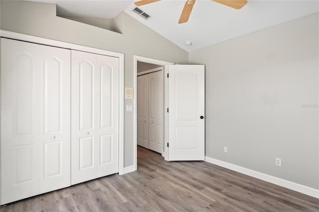 unfurnished bedroom featuring baseboards, visible vents, wood finished floors, vaulted ceiling, and a closet