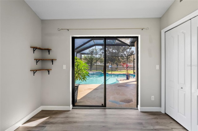 doorway to outside featuring a sunroom, baseboards, and wood finished floors