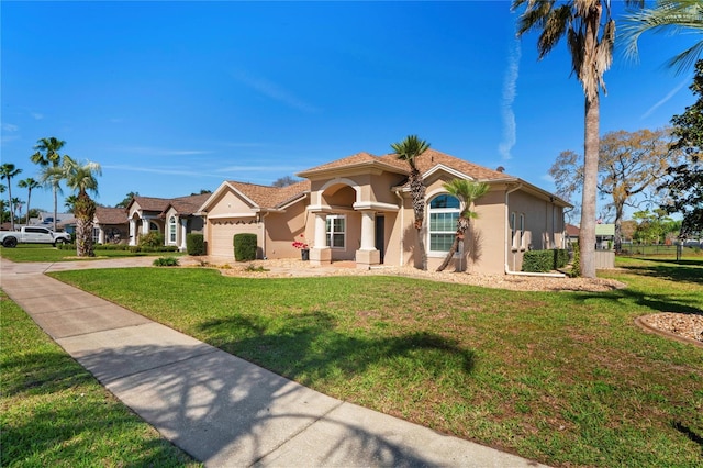 mediterranean / spanish-style house featuring a garage, a front yard, driveway, and stucco siding