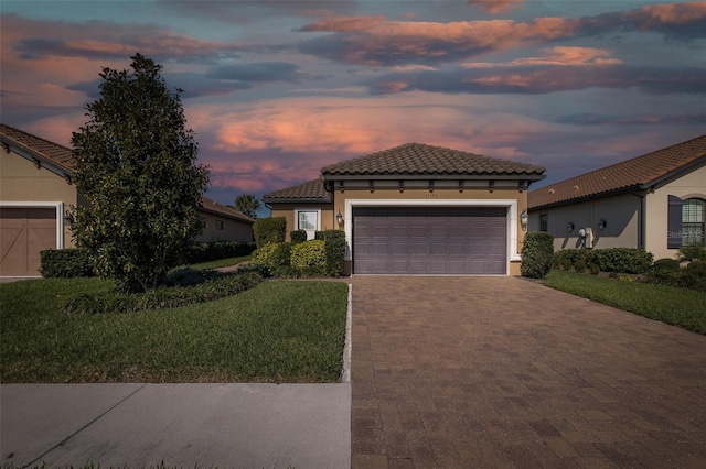 mediterranean / spanish house featuring a tiled roof, decorative driveway, an attached garage, and stucco siding