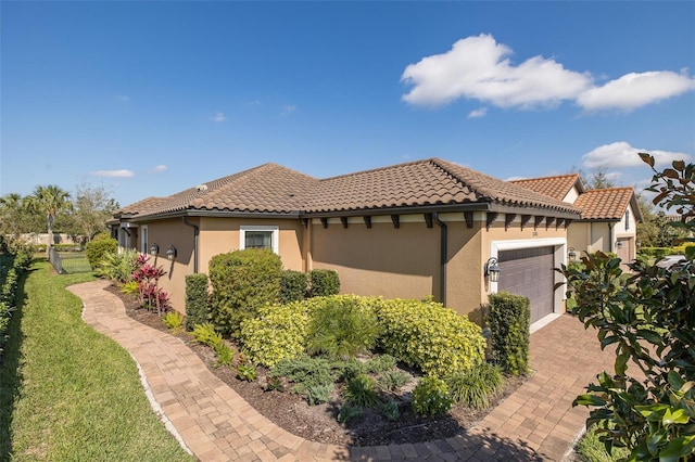 view of front of home featuring a garage, a tiled roof, a front yard, and stucco siding