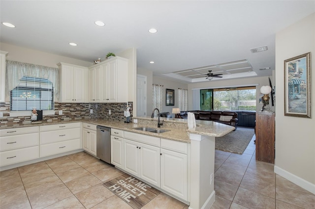 kitchen featuring a raised ceiling, open floor plan, a sink, dishwasher, and a peninsula