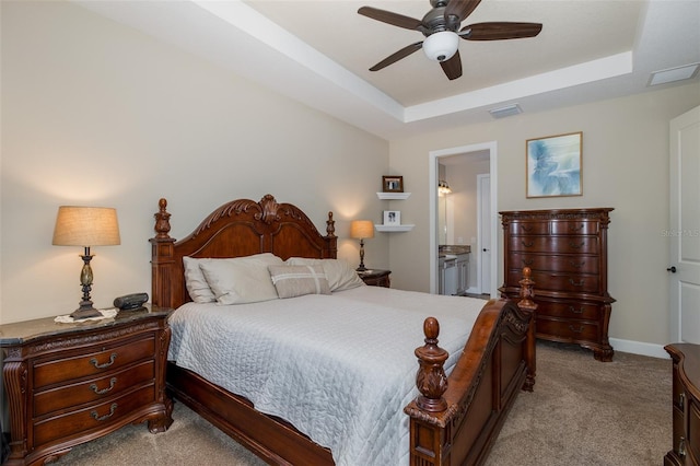 carpeted bedroom with ceiling fan, a tray ceiling, visible vents, and baseboards