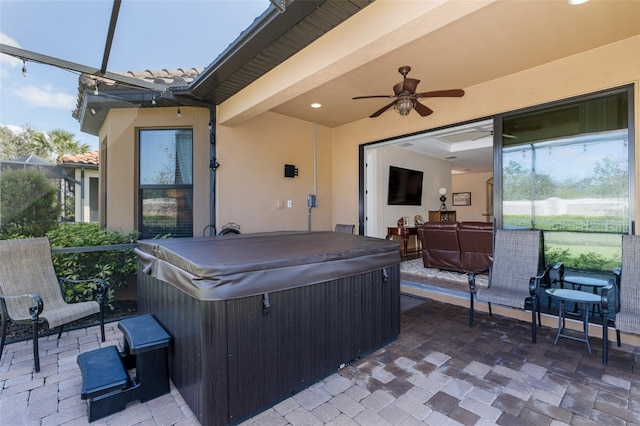 view of patio / terrace with a lanai, a ceiling fan, and a hot tub