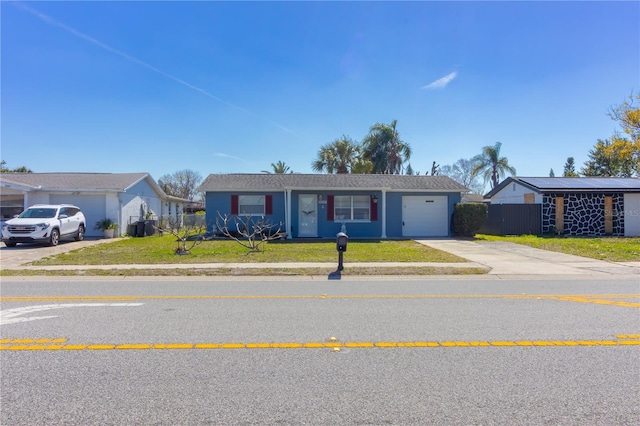 ranch-style house with concrete driveway, an attached garage, a front lawn, and fence