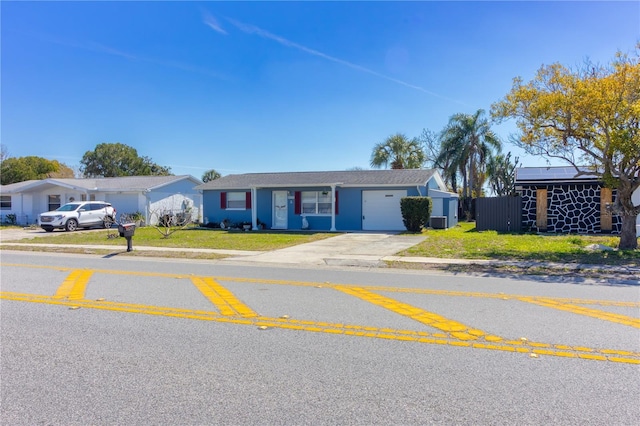 single story home featuring a front lawn, concrete driveway, an attached garage, and central air condition unit