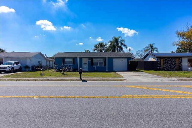 single story home featuring a front yard, driveway, an attached garage, and fence