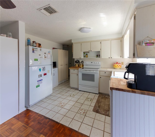 kitchen with butcher block counters, visible vents, a sink, a textured ceiling, and white appliances