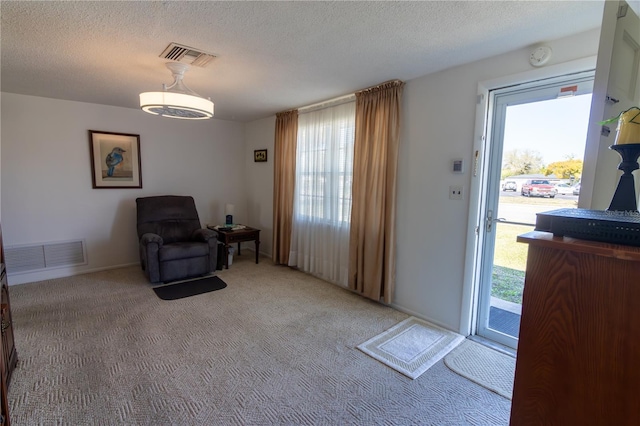 living area with a textured ceiling, carpet, and visible vents