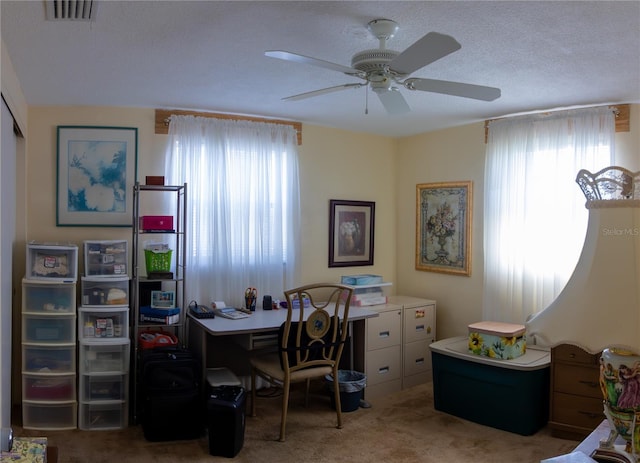 office space with a ceiling fan, visible vents, a textured ceiling, and light colored carpet