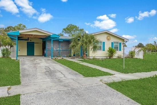 ranch-style home featuring an attached carport, concrete driveway, and a front yard