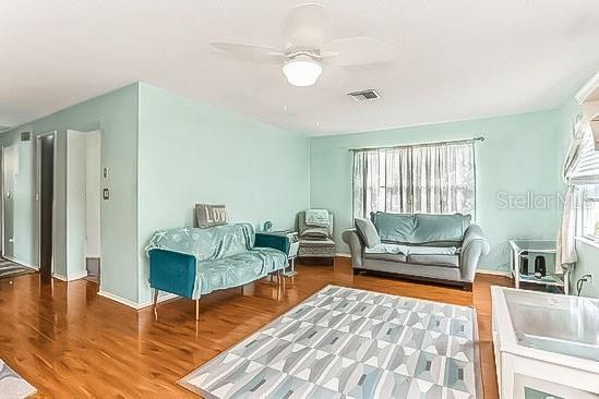 sitting room featuring visible vents, ceiling fan, and wood finished floors