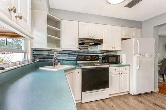 kitchen featuring black microwave, under cabinet range hood, a sink, freestanding refrigerator, and electric range oven