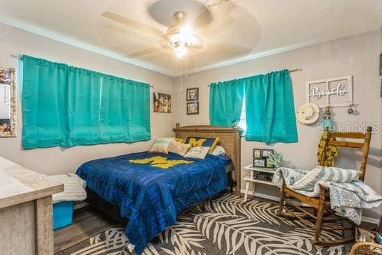 bedroom with ceiling fan, wood finished floors, and baseboards