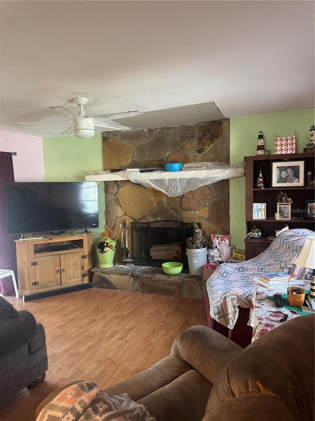 living area with ceiling fan, a fireplace, and wood finished floors