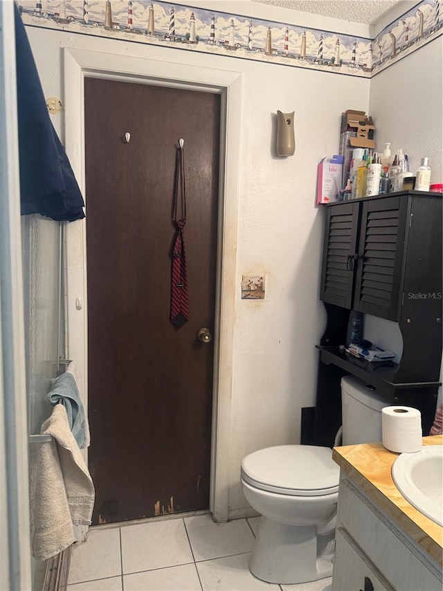 bathroom with toilet, vanity, a textured ceiling, and tile patterned floors