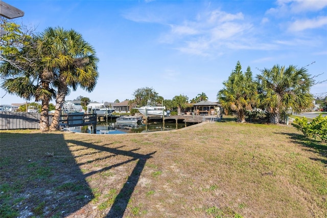 dock area featuring a water view, fence, and a yard