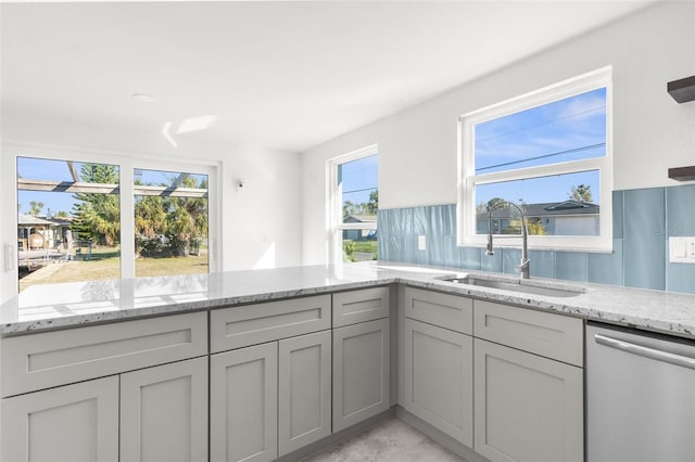 kitchen with gray cabinets, dishwasher, a sink, and light stone countertops