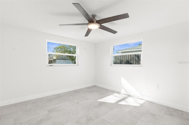 spare room with ceiling fan and baseboards