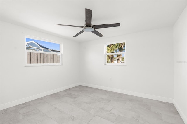 spare room featuring a ceiling fan and baseboards