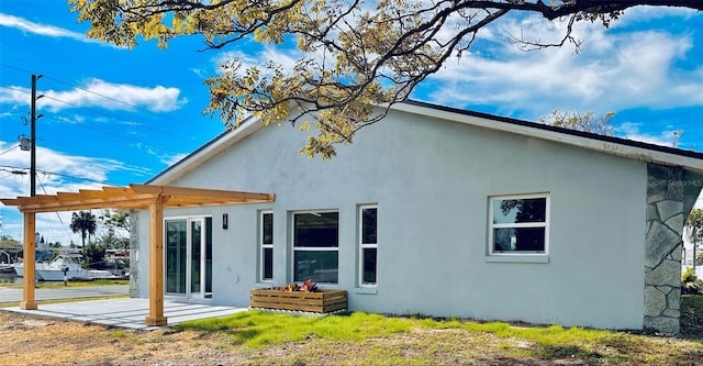 back of house featuring a pergola, a patio area, and stucco siding