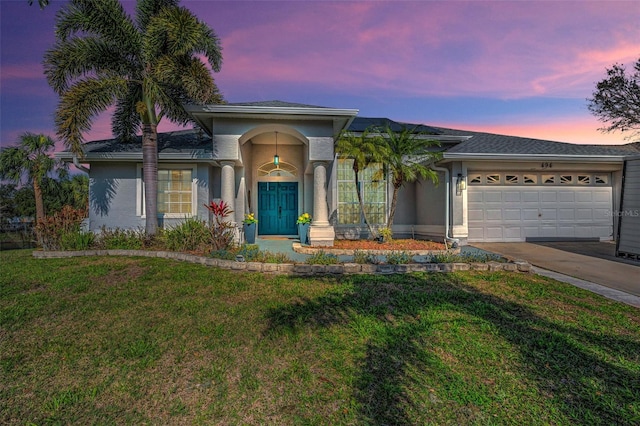 view of front of house featuring a lawn, an attached garage, and stucco siding