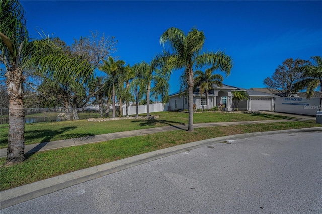 view of front facade with an attached garage, driveway, fence, and a front yard