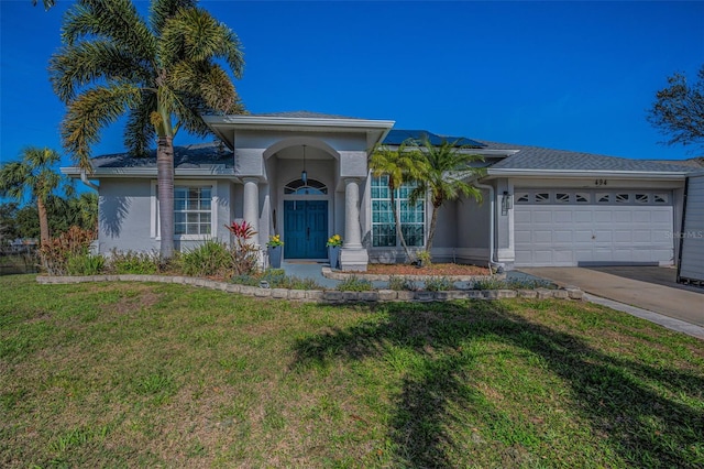 view of front of property featuring a garage, driveway, a front lawn, and stucco siding