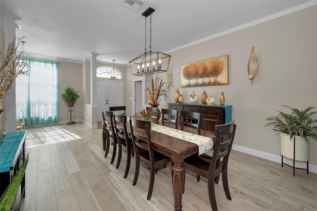 dining space featuring crown molding, light wood-style flooring, and ornate columns