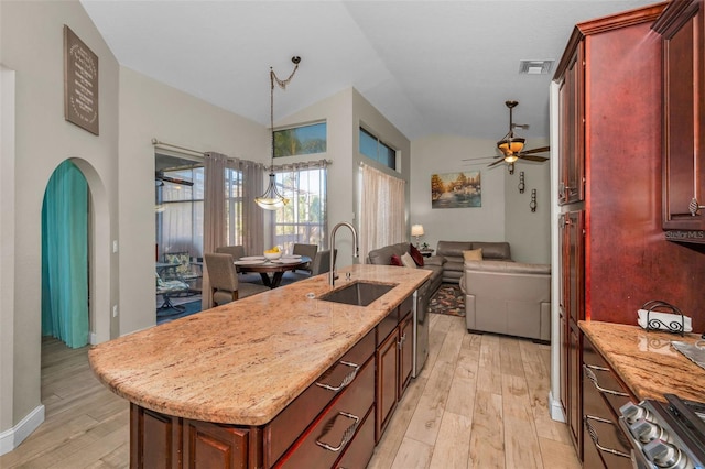 kitchen with arched walkways, light wood finished floors, visible vents, open floor plan, and a sink