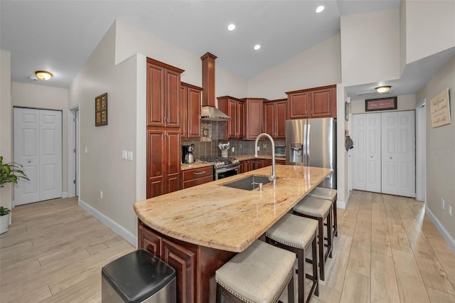 kitchen with a breakfast bar, stainless steel appliances, backsplash, light wood-style floors, and a sink