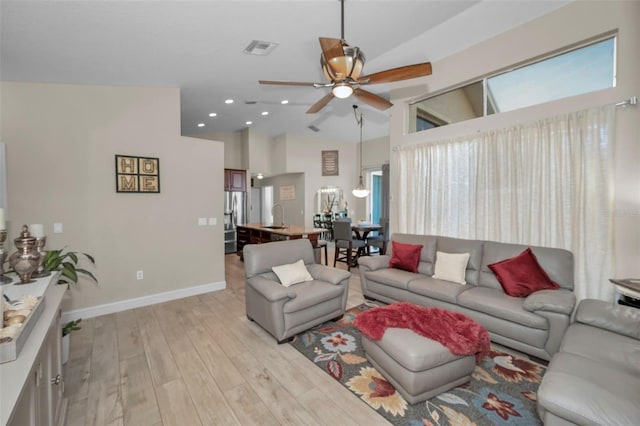 living area featuring lofted ceiling, ceiling fan, visible vents, baseboards, and light wood-type flooring