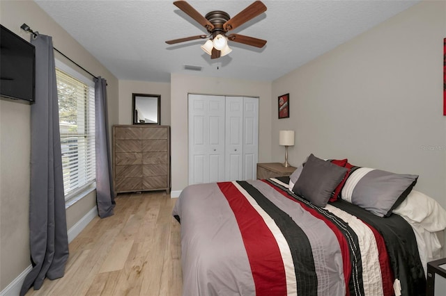 bedroom featuring a textured ceiling, a closet, visible vents, and light wood-style floors