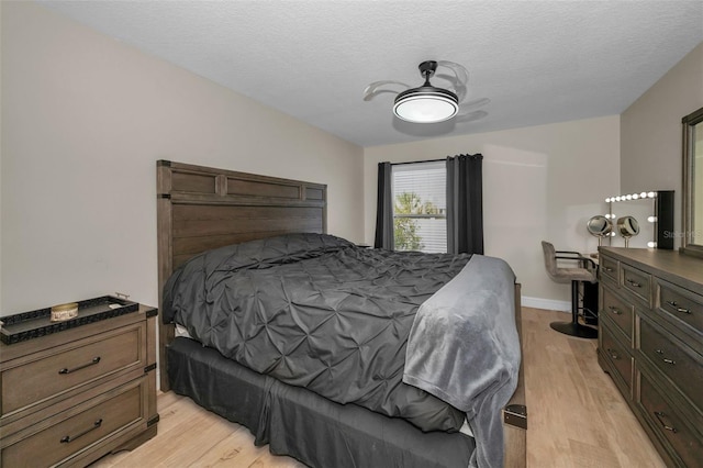 bedroom with light wood-type flooring, a textured ceiling, and baseboards