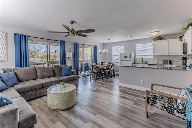 6183 Waverly Rd, Weeki Wachee, FL 34607 - living area featuring a chandelier, a ceiling fan, light wood-style floors, and baseboards