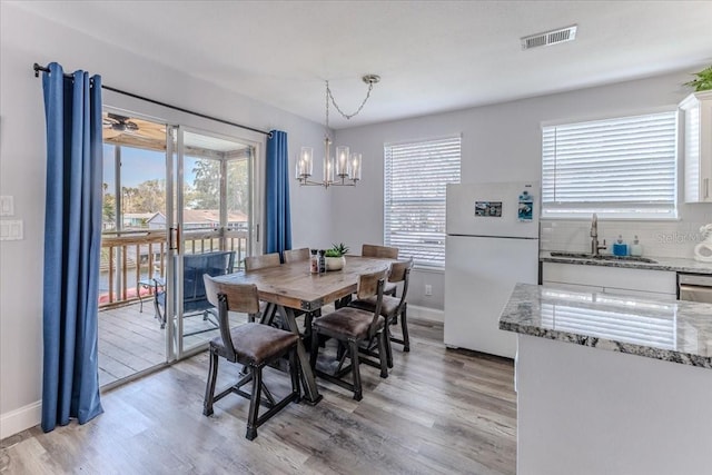 6183 Waverly Rd, Weeki Wachee, FL 34607 - dining area with a chandelier, light wood-type flooring, and baseboards